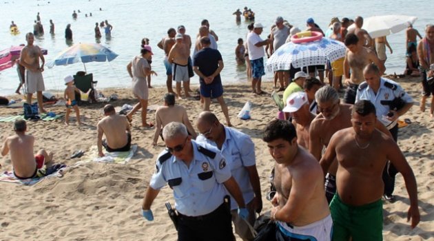 Plajdakiler kıyıdaki cesede aldırmaksızın yüzdü